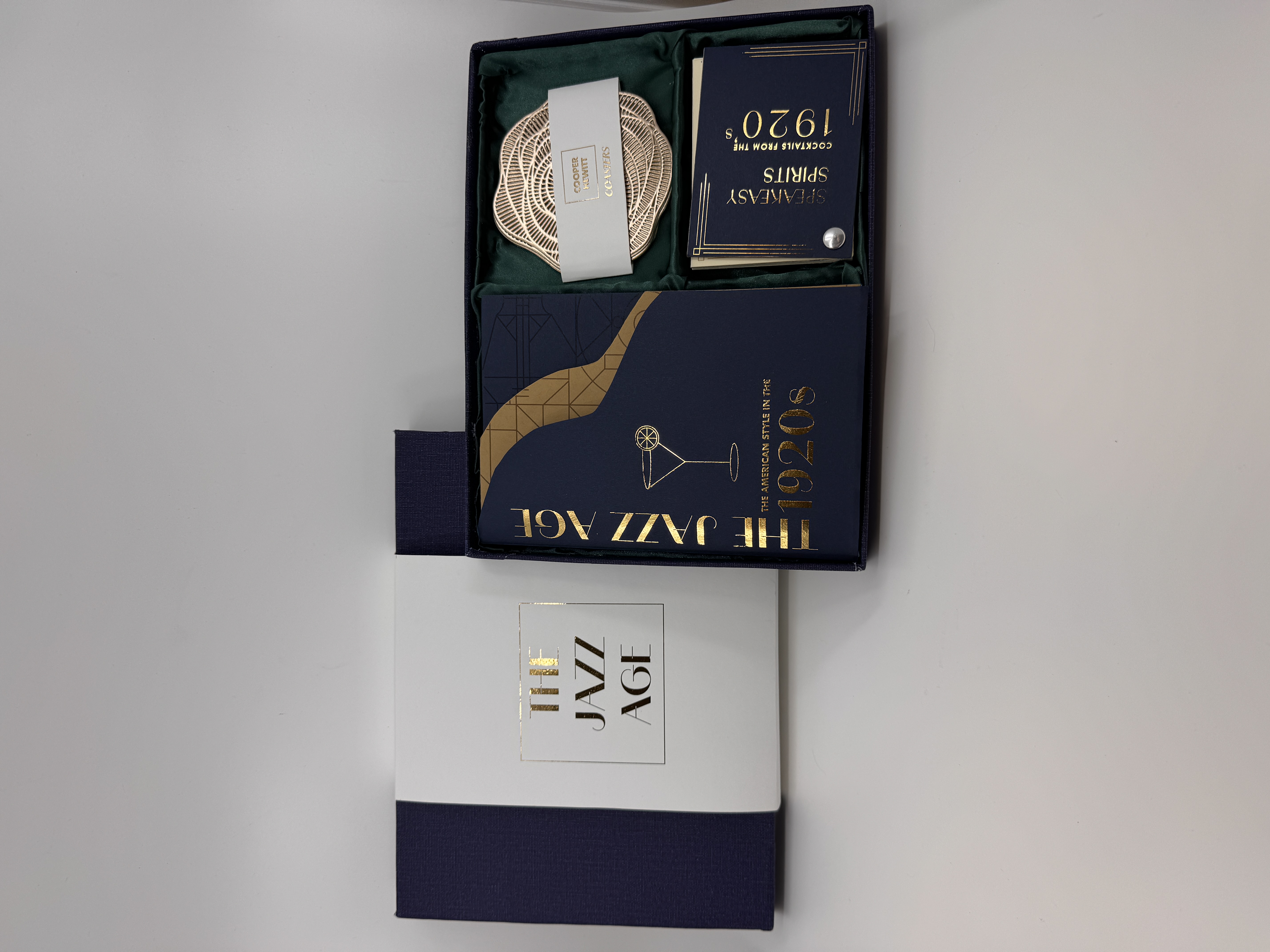 Opened box showing different elements on the inside, including two books and coasters