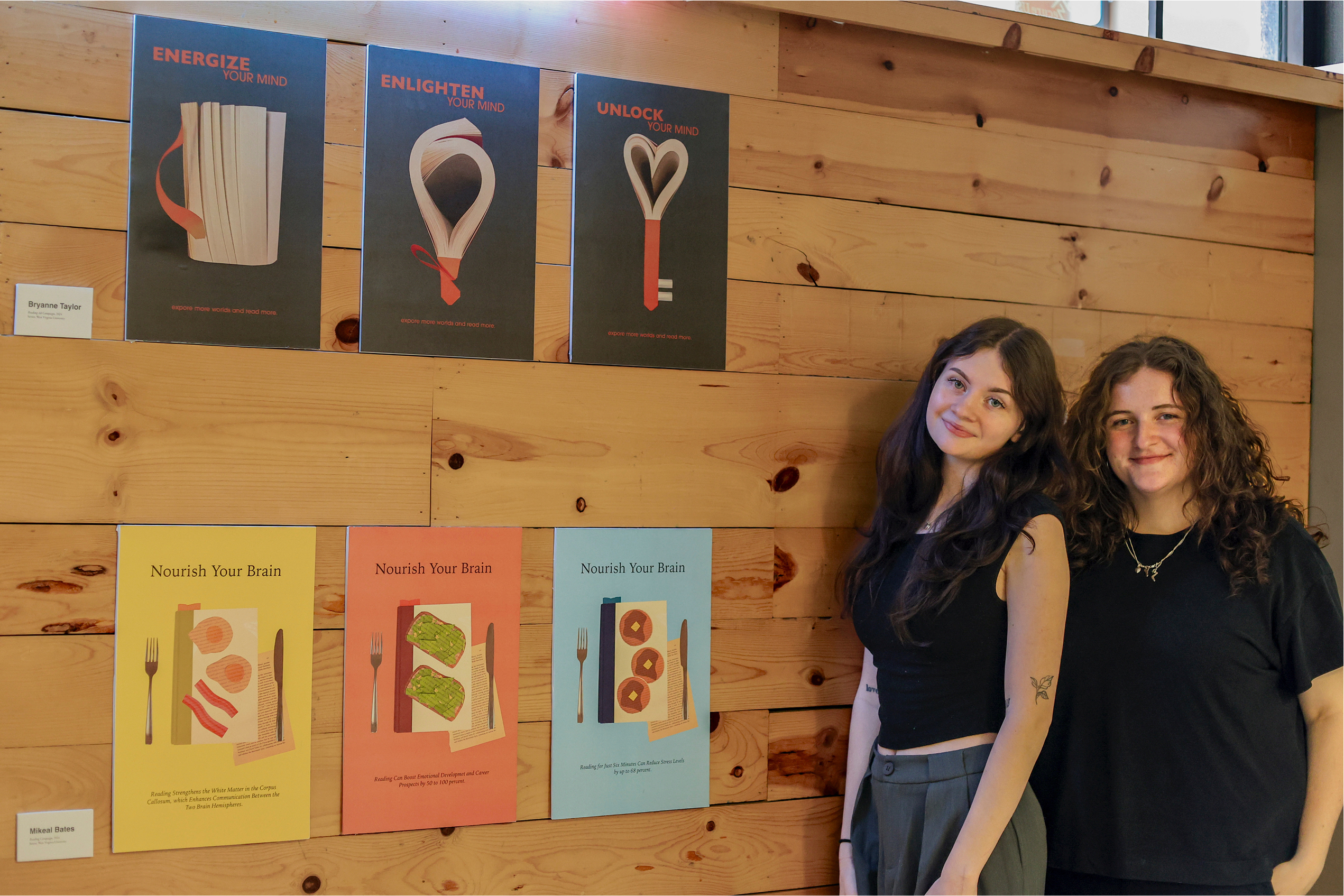 Bryanne Taylor and Mikeal Bates standing next to each other by a wall which displays the ad campaigns